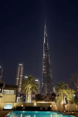 a tall building at night with a pool in front of it at Live the Burj Lifestyle in Timeless OldTown by SBH in Dubai