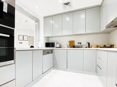 a white kitchen with white cabinets and appliances at Live the Burj Lifestyle in Timeless OldTown by SBH in Dubai