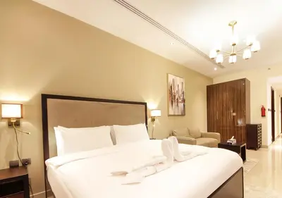 a bedroom with a large white bed and a living room at Elite Downtown Stay with Gym, Pool near Dubai Mall in Dubai