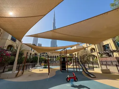 a playground with a slide and a swing set at Durrani Homes - Luxe Living at Souk Al Bahar with Burj Khalifa and partial Fountain view in Dubai