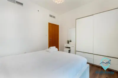 a white bedroom with a large mirror and a bed at 1BR Cozy and Bright Dubai Marina in Dubai