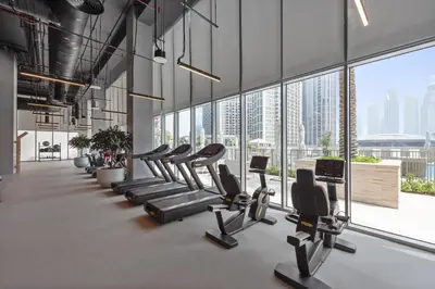 a gym with a row of treadmills and a large window at VayK - Luxury 1BR in Downtown in Dubai