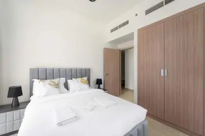 a bedroom with a large white bed and a wooden cabinet at VayK - Modern 3BR with a Spacious Terrace in Dubai