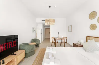 a bedroom with a bed and a tv and chairs at VayK - Stylish & Cozy Studio in JVC in Dubai