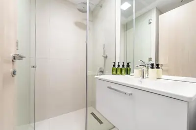 a white bathroom with a sink and a shower at VayK - Stylish & Cozy Studio in JVC in Dubai