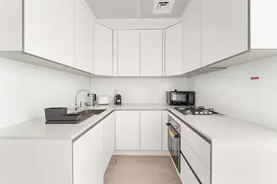 a white kitchen with white cabinets and appliances at VayK - Stylish & Cozy Studio in JVC in Dubai