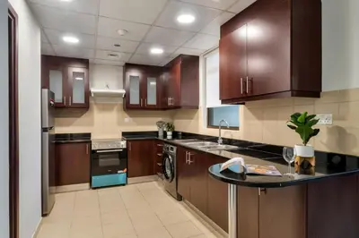 a kitchen with wooden cabinets and a black counter top at Enchanting Stay in JBR Near The Beach in Dubai