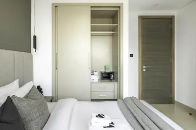 a bedroom with a white bed and a mirror at New 2BR with Pool and Gym in Green Sobha Community in Dubai