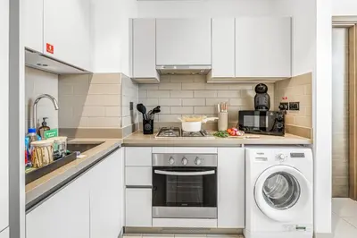 a kitchen with white cabinets and a washer at New 2BR with Pool and Gym in Green Sobha Community in Dubai