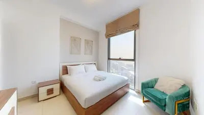 a bedroom with a bed and a chair and a window at Vacationer I Exclusive 2 Bedroom I Breathtaking Skyline & City Views I Afnan 1 - IMPZ in Dubai