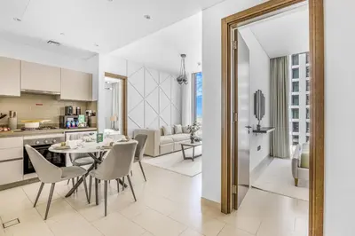 a kitchen and living room with a table and chairs at New 2BR with BBQ Area, Pool in Sobha MBR City in Dubai