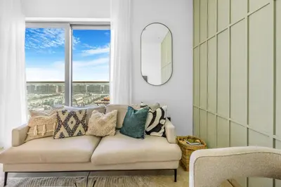 a living room with a couch and a window at Stylish 1BR with Pool, BBQ Area, Gym in MBR City in Dubai