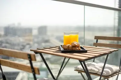 a table with a glass of orange juice and a plate of food at Stylish 1BR with Pool, BBQ Area, Gym in MBR City in Dubai