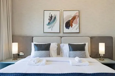 a bedroom with a large white bed with three pictures on the wall at Burj & Fountain View 5-Min Walk to Dubai Mall in Dubai