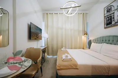 a bedroom with a bed and a desk and a table at Stylish studio in Azizi 42 in Dubai