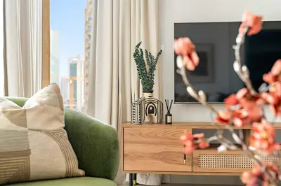 a living room with a green couch and a table with flowers at Silkhaus Elite 1BDR at 29 Boulevard Downtown in Dubai
