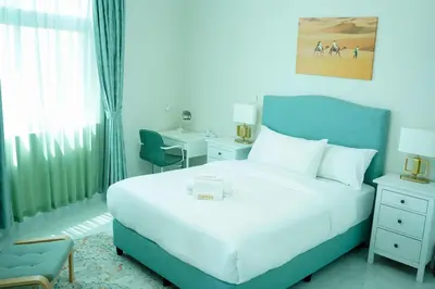 a bedroom with a large white bed and a chair at Zapbed House-Cozy 2 BR Apartment In The Greens Golf View in Dubai
