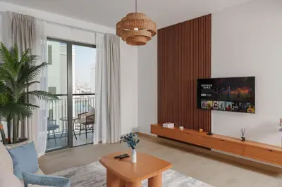 a living room with a couch and a tv on a wall at High-End Luxury 1BR in Port De La Mer near J1 Beachfront, Dubai in Dubai