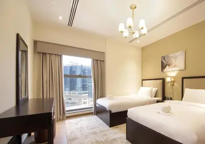 a hotel room with two beds and a desk and a window at Luxury 3BR Apartment By Elite Residence Downtown in Dubai