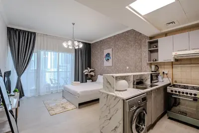 a kitchen and living room with a stove and a couch at Stylish Studio apartment in Downtown Dubai in Dubai