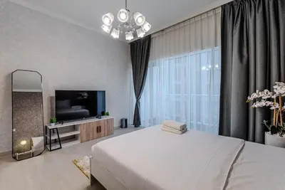 a bedroom with a large white bed and a television at Stylish Studio apartment in Downtown Dubai in Dubai