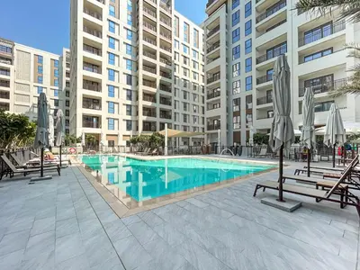 a swimming pool with chairs and umbrellas next to a building at Chic Bright Home in Creek Beach with Lagoon Access in Dubai