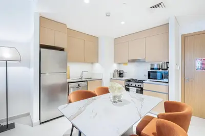 a kitchen with a table and chairs and a refrigerator at Chic Bright Home in Creek Beach with Lagoon Access in Dubai