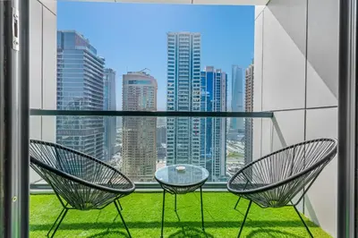 a balcony with two chairs and a glass table at Waves- Cozy 1BR Lakefront Stay in JLT in Dubai