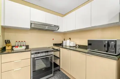 a kitchen with white cabinets and a stove and microwave at Waves- Cozy 1BR Lakefront Stay in JLT in Dubai