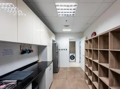 a kitchen with white walls and wooden cabinets and a refrigerator at Female - Girls Joyful Journeys - girls only bedspace in Dubai