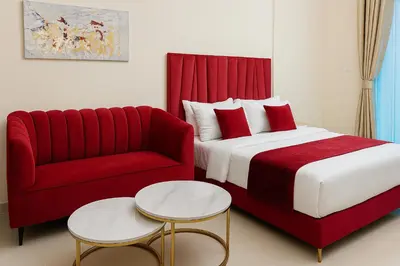 a bedroom with a red bed and a red couch at Comfy Studio in JVC Great Location Fast Wi-Fi in Dubai