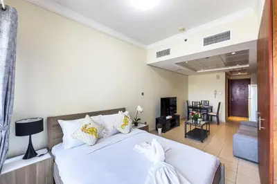 a bedroom with a white bed and a living room at Chill Studio with Balcony and Pool View in Dubai