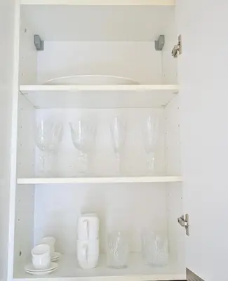 a white cupboard filled with glasses and plates at Studio on the 30th Floor with Stunning Marina View in Dubai