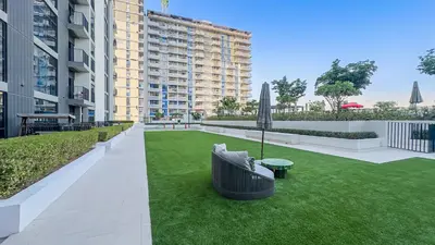 a garden with a large building in the background at Escape24 Elegant 2BR with Garden View in Dubai Hills in Dubai