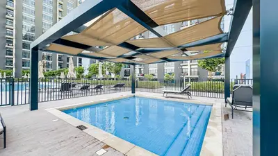 a swimming pool with a wooden canopy over it at Escape24 Elegant 2BR with Garden View in Dubai Hills in Dubai