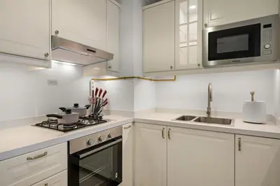 a white kitchen with a stove and a microwave at FIRST CLASS 1BR Spacious Comfort Awaits in Dubai