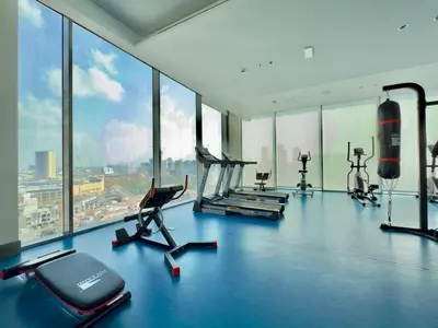 a gym with cardio equipment in a large room with windows at Brand New - Fully Furnished Premium 1BR in JVC in Dubai