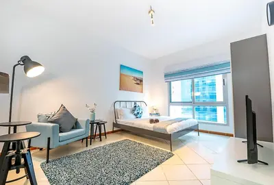 a living room with a bed and a couch and a tv at Cozy Chic Studio l Next to Marina Mall in Dubai