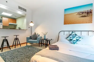 a bedroom with a bed and a table and a chair at Cozy Chic Studio l Next to Marina Mall in Dubai