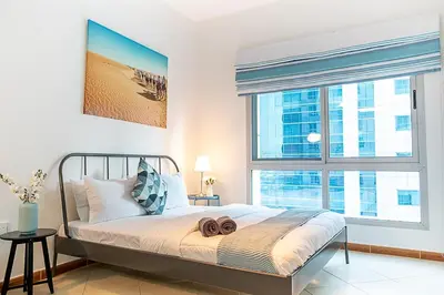 a bedroom with a bed and a large window at Cozy Chic Studio l Next to Marina Mall in Dubai