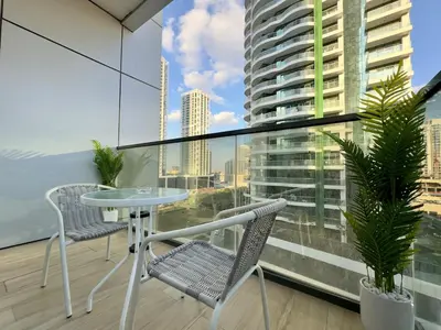 a balcony with a table and chairs and a large window at Brand New-Fully Furnished Classy Studio In JVC in Dubai