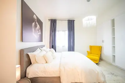 a bedroom with a white bed and a yellow chair at 1BHK Luxury Serviced Apartment - Al Andalus JGE in Dubai