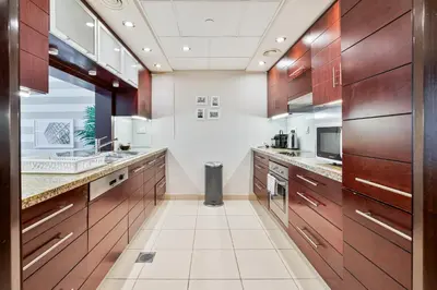 a large kitchen with wooden cabinets and a sink at Vibrant 1BR APT with Burj Khalifa View in Dubai