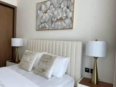 a bed with white pillows and a painting on the wall at Elegant Jvc 1br Balcony, Pool Access, Parking in Dubai