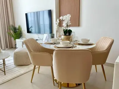 a dining room with a table with chairs and a television at Elegant Jvc 1br Balcony, Pool Access, Parking in Dubai