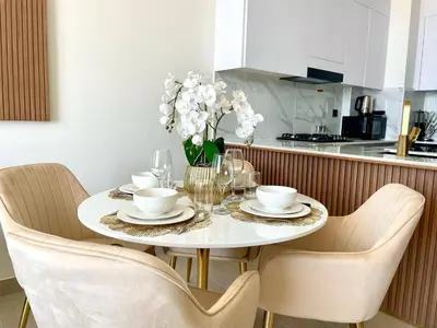 a dining room table with chairs and a white table with glasses at Elegant Jvc 1br Balcony, Pool Access, Parking in Dubai
