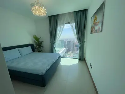 a bedroom with a bed and a window with a chandelier at Vida Dubai Marina Apartment at Prime Location in Dubai