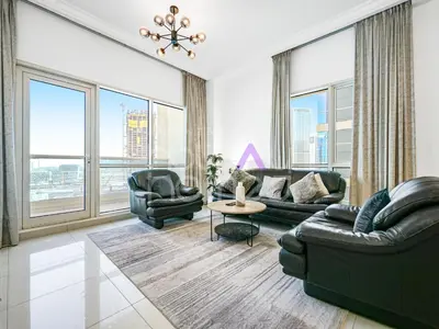 a living room with leather furniture and large windows at Modern 1BR Oasis II Huge Layout II City Lights in Dubai