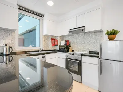 a kitchen with white cabinets and a stainless steel refrigerator at Modern 1BR Oasis II Huge Layout II City Lights in Dubai