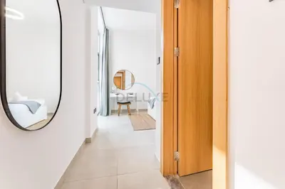 a hallway with a mirror and a table at Balcony Offering Community Views 1BR with Assistant Room, Walking Distance to Community Park , Pantheon Elysee , Jumeirah Village Circle by Deluxe Holiday Homes in Dubai